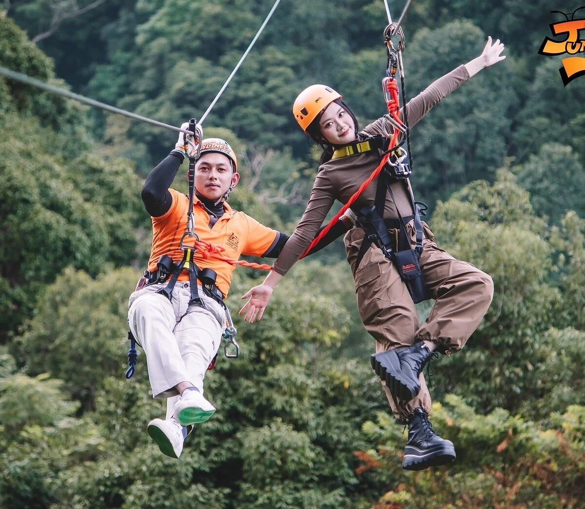 Two adventurers on tandem zipline through forest canopy