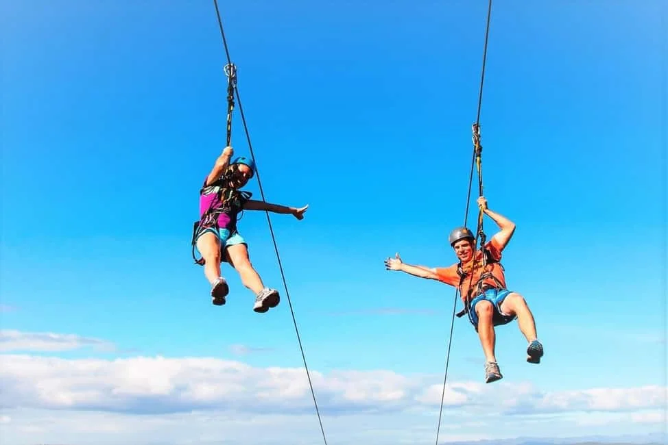 Adventurers on giant swing soaring above jungle